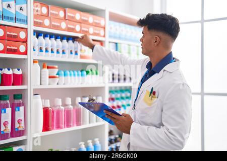Junger hispanischer Apotheker, der auf einem Dokument in der Apotheke schreibt Stockfoto