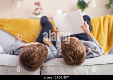 Niedliche Jungs, die zu Hause auf dem Sofa ein Buch lesen Stockfoto