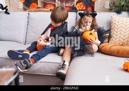 Ein süßer Junge und ein süßes Mädchen, die zu Hause eine halloween-Party feiern und Kürbis malen Stockfoto