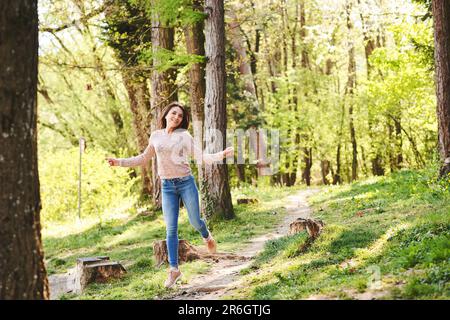 Fit, junge Frau, die im Morgenwald wandert, Mädchen voller Energie, die glücklich springt Stockfoto