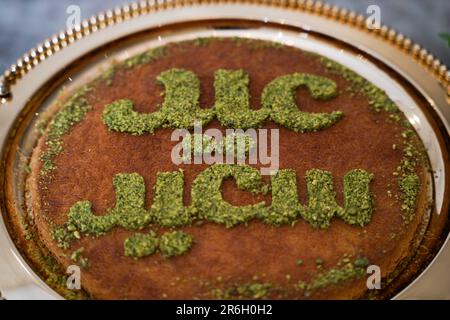 Nachtisch oder Kuchen am Feiertag. Kunafa ist bekannt für arabische Süße mit Happy Eid Schriftzug auf dem Gipfel der Wüste. Stockfoto