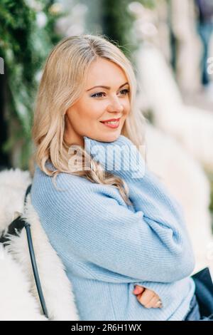 Winterporträt einer schönen Frau mit blondem Haar, die einen blauen Pullover trägt Stockfoto