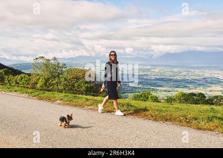 Außenporträt einer hübschen Frau, die mit einem Yorkshire Terrier-Hund spaziert Stockfoto