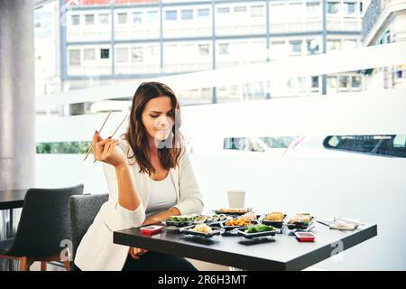 Junge Frau isst Geschäftsessen im Sushi-Restaurant Stockfoto