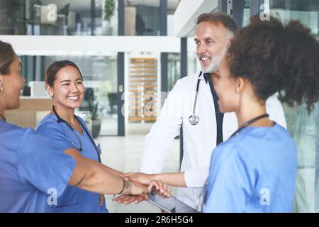 Waren unaufhaltsam, als wir zusammen waren. Eine vielfältige Gruppe von medizinischen Fachkräften, die zusammengedrängt stehen und ihre Hände in der Mitte stapeln. Stockfoto
