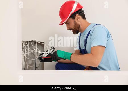 Elektriker mit schraubendrehbarem Patchpanel im Innenbereich Stockfoto