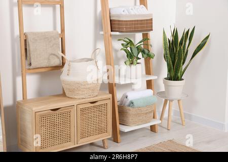 Weiche Handtücher auf dekorativer Leiter nahe der weißen Wand Stockfoto