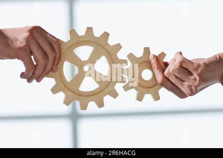 Zwei Geschäftsleute vereinen Zahnräder aus Holz, Nahaufnahme Stockfoto