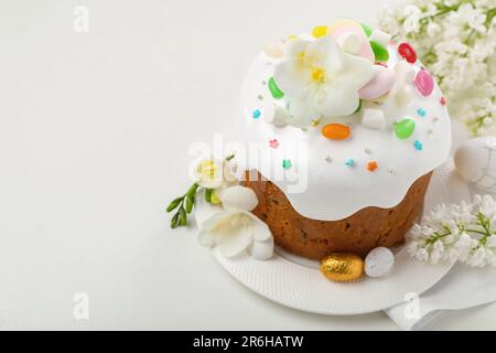 Traditioneller Osterkuchen mit bemalten Eiern und Blumen auf weißem Tisch, Platz für Text Stockfoto