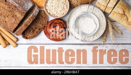 Verschiedene glutenfreie Produkte und Text auf weißem Holztisch, Draufsicht Stockfoto