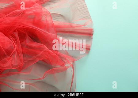 Wunderschönes rotes Tullgewebe auf türkisfarbenem Hintergrund, Nahaufnahme Stockfoto