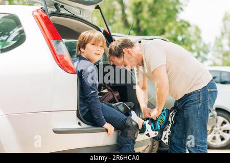 Vater hilft dem kleinen Sohn, die Schnürsenkel zu binden, aktive Zeit mit der Familie Stockfoto