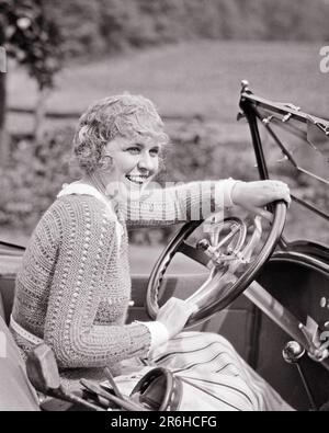 1920S SPORTLICH LÄCHELNDE GOLFERIN MIT PULLOVER, DIE HINTER DEM LENKRAD EINES CABRIOLETS SITZT – M164 HAR001 HARS STYLE LAUGH BLOND FAHRZEUG JUNGER ERWACHSENER SPORTLER ERFREUT FREUDE LEBENSSTIL ZUFRIEDENHEIT FRAUEN GESUNDHEIT KOPIERER HALBE LÄNGE DAMEN PERSONEN AUTO GOLF LEICHTATHLETIK SELBSTVERTRAUEN TRANSPORT AUSDRÜCKE B&W GLÜCK FRÖHLICHES ABENTEUER GOLFER FREIZEIT AUTOS AUFREGUNG ERHOLUNGSMANSCHETTEN STOLZ LÄCHELT AUTOS FRÖHLICHE LINKS STILVOLLE FAHRZEUGE GOLFSCHLÄGER JUNGE ERWACHSENE FRAU SCHWARZ-WEISS WEISSE ETHNISCHE ZUGEHÖRIGKEIT HAR001 ALTMODISCH Stockfoto