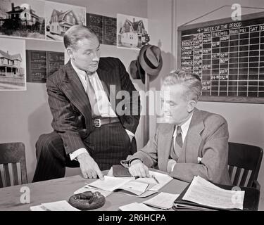 1930S 1940S ZWEI IMMOBILIENMAKLER IM BÜRO, DIE PAPIERFOTOS VON HÄUSERN AN WÄNDEN UND KREIDETAFELN DURCHGEHEN ZEITPLAN - O1676 HAR001 HARS TEAMWORK INFORMATIONEN FOTOS LIFESTYLE ARCHITEKTUR HÄUSER JOBS KOPIEREN PLATZ HALBLANG MÄNNER GEBÄUDE ECHTE WESTE MITTLEREN ALTERS B&W MÄNNER MITTLEREN ALTERS ZIELE QUALIFIKATIONSANZUG UND KRAWATTE BESCHÄFTIGUNG SELLING SKILLS IMMOBILIENSTRATEGIE UND ARBEITSMÖGLICHKEITEN BESCHÄFTIGUNG JOBS PLANEN REAL DREITEILIGE ANZÜGE VON ESTATE REALTOR STILVOLLE AGENTEN GEBÄUDE MITARBEITERZUSAMMENARBEIT MITTELERWACHSENER MANN NADELSTREIFENANZUG IMMOBILIENVERKÄUFER ZUSAMMENGEHÖRIGKEIT SCHWARZ UND WEISS Stockfoto