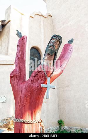 Vertikales Bild einer hölzernen Christusstatue aus einem bemalten Baumstumpf in der St. Joseph's Church in Cerrillos New Mexico, USA. Stockfoto