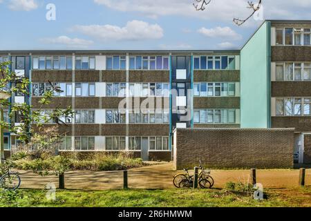 Ein Apartmentkomplex mit Fahrrädern, die auf den Bürgersteigen davor geparkt sind, und einigen Gebäuden auf der linken Seite Stockfoto