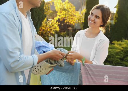 Glückliche Familie, die Kleidung aufhängt, mit Wäscheklammern an der Wäscheleine, um im Garten zu trocknen Stockfoto