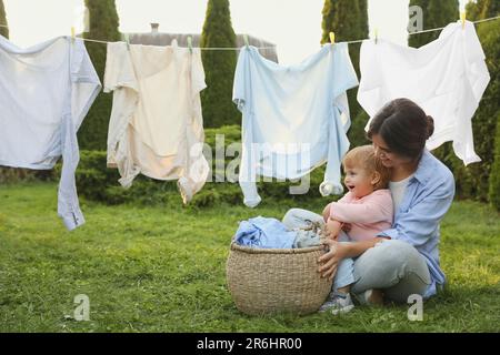 Mutter und Tochter in der Nähe der Wäscheleine mit trocknender Kleidung im Garten Stockfoto