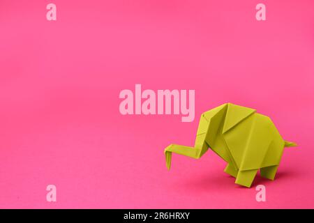 Gelber Papierelefant auf pinkfarbenem Hintergrund, Platz für Text. Origami-Kunst Stockfoto