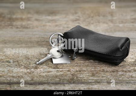 Ledertasche mit Schlüssel auf altem Holztisch, Nahaufnahme. Platz für Text Stockfoto