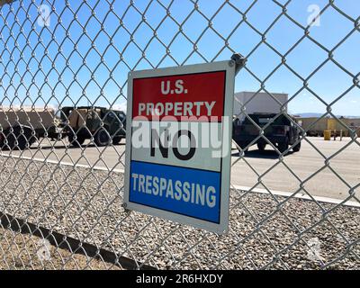 USA An einem Kettenglied angebrachtes Schild für die Eigenschaft „kein Betreten“. Unscharfe Militärausrüstung, Fahrzeuge im Hintergrund. Stockfoto