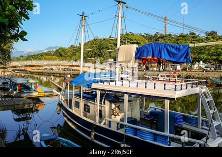 Touristenboot auf dem Fluss Pereqe-Acu mit großem Hintergrund an einem sonnigen Tag in der UNESCO-Weltkulturerbe-Stadt Paraty, Brasilien Stockfoto