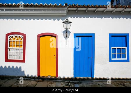 Weiße Hausfassaden mit blauen und gelben Türen und Fenstern an sonnigen Tagen in der historischen Stadt Paraty, Brasilien, UNESCO-Weltkulturerbe Stockfoto