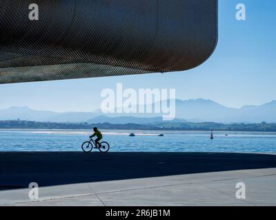 Silhouetten von Menschen, die entlang eines Kais im Hafen von Santander spazieren. Stockfoto