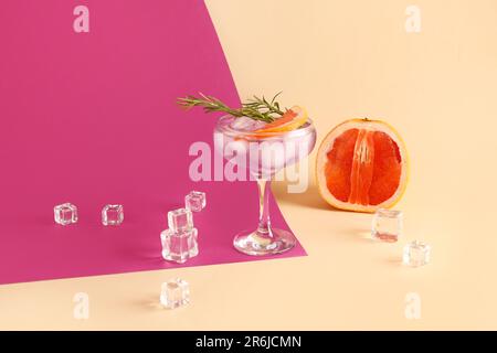 Purpurfarbener Gin und Tonic mit Eiswürfeln auf farbigem Hintergrund Stockfoto