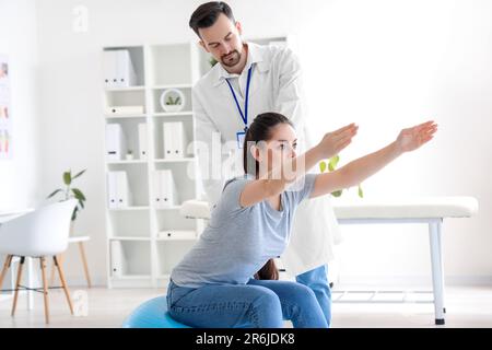 Männlicher Physiotherapeut im Rehabilitationszentrum mit junger Frau Stockfoto