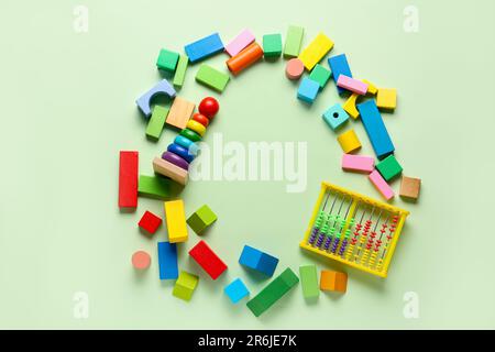 Rahmen aus verschiedenen bunten Spielzeugen auf grünem Hintergrund. Feierlichkeiten zum Kindertag Stockfoto