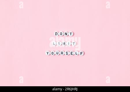 Draufsicht der Zitate „Do't Limit Yourself“ aus Perlen auf pinkfarbenem Hintergrund. Motivation und Erfolgskonzept Stockfoto