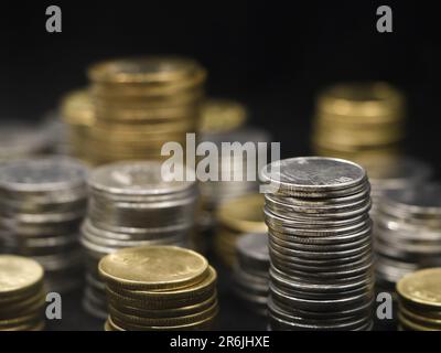 Nahaufnahme von Reihen mit Gold- und Silbermünzen, die in Türmen unterschiedlicher Größe angeordnet und gestapelt sind, isoliert auf schwarzem Hintergrund Stockfoto