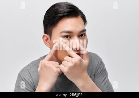 hübscher junger Mann Squeezing Pickel Stockfoto