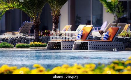 Sonnenliegen an einem Swimmingpool in einem luxuriösen subtropischen Resort Stockfoto