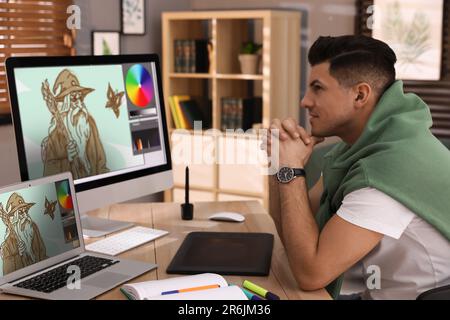 Animator, der mit Computer und Laptop arbeitet. Abbildungen auf Bildschirmen Stockfoto