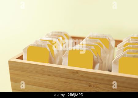 Holzbox mit Teebeuteln auf hellgrünem Hintergrund, Nahaufnahme Stockfoto