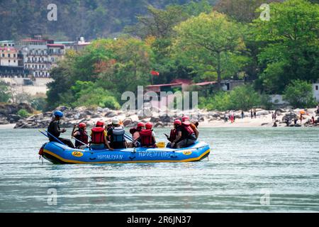 Freunde der Familie, die im Floß sitzen und Abenteuersportarten genießen, während sie vor GHAT und Tempel am Ufer des heiligen Flusses ganga überqueren Stockfoto