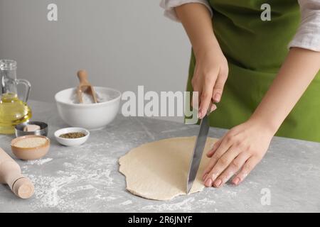 Frau schneidet Teig auf einem hellgrauen Marmortisch, Nahaufnahme. Ich koche Grissini Stockfoto