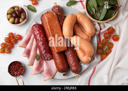Verschiedene leckere Wurstsorten und Zutaten auf weißem Tisch, flach liegend Stockfoto