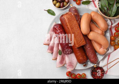 Verschiedene leckere Wurstsorten und Zutaten auf weißem Tisch, flach liegend. Platz für Text Stockfoto