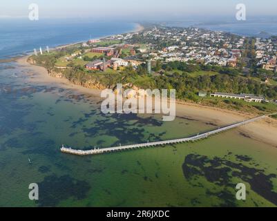 Luftaufnahme einer langen Anlegestelle vor einer Küstenstadt auf einer Halbinsel, umgeben vom Meer in Queenscliff in Victoria, Australien Stockfoto