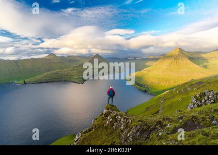 Wanderer mit Rucksack genießen die Aussicht auf Felsen mit Blick auf Funningur Fjord, Eysturoy Island, Färöer Inseln, Dänemark, Europa Stockfoto