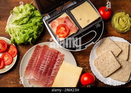 Sandwichmacher. Sandwiches mit verschiedenen Füllungen zubereiten. Stockfoto