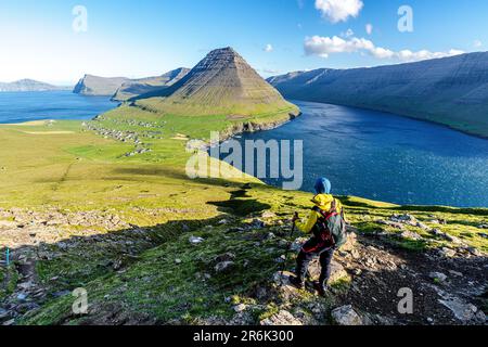 Wanderer auf dem Hügel mit Vidareidi Dorf und Malinsfjall Berg im Hintergrund, Vidoy Island, Färöer Inseln, Dänemark, Europa Stockfoto