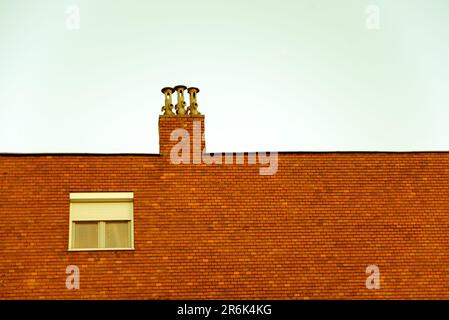 Backsteinhauswand mit Fenster und Herdplatten Stockfoto