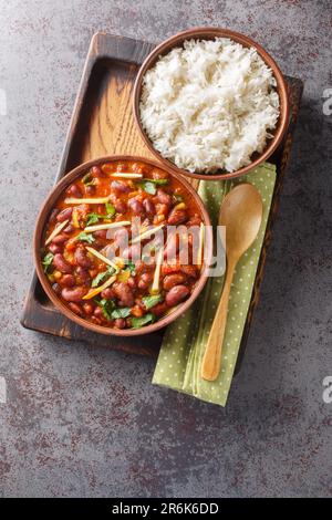 Rajma Masala ist eine köstliche Soße, die durch Kochen von roten Bohnen mit Zwiebeln, Tomaten und einfachen Gewürzen mit Reis aus nächster Nähe auf einem Holztablett auf der Ta hergestellt wird Stockfoto