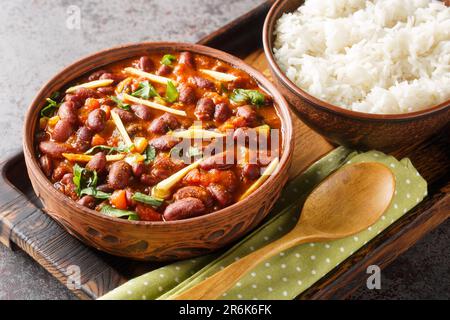 Rajma Masala ist ein beliebtes nordindisches Gericht mit roten Kidney Beans und Reis aus nächster Nähe auf einem Holztablett auf dem Tisch. Horizontal Stockfoto