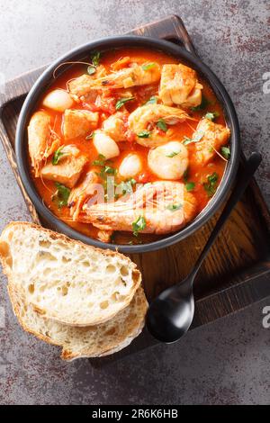 Mediterraner, dicker Eintopf aus Meeresfrüchten und Fisch mit Tomaten aus nächster Nähe in einer Schüssel auf dem Tisch. Vertikale Draufsicht von oben Stockfoto