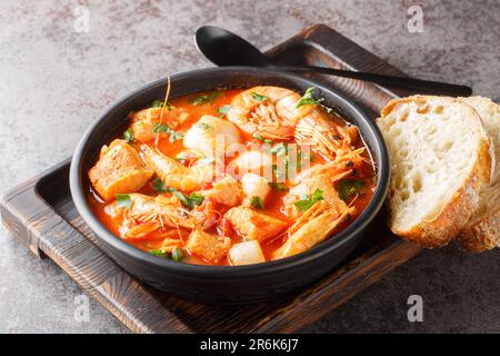 Mediterrane Suppe mit Meeresfrüchten und weißem Fisch mit Garnelen, Muscheln, Jakobsmuscheln und Tintenfisch aus nächster Nähe in einer Schüssel auf dem Tisch. Horizontal Stockfoto